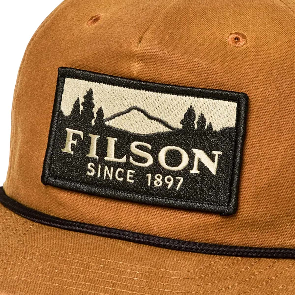 Filson Waxed Trucker Cap Gold Brown/Scenic, een klassieke gewaxte trucker cap, afgewerkt met een opvallende geborduurde Filson Scenic patch &ndash; ontworpen voor stijl en duurzaamheid